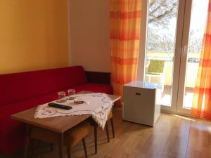 a living room with a table and a red couch at Summer rooms Baška in Baška
