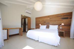 a bedroom with a large white bed with a wooden headboard at Rio Búzios Boutique Hotel in Búzios