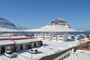 un complexe dans la neige avec une montagne en arrière-plan dans l'établissement The Old Post Office Guesthouse, à Grundarfjörður