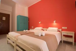 two beds in a room with a red wall at Niki Rooms in Palaiochora