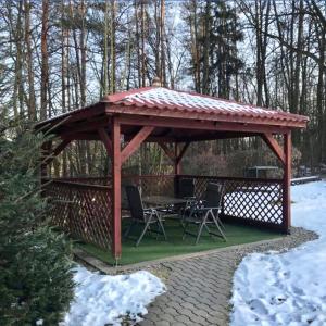 a wooden gazebo with a table and chairs in the snow at Apartmans Les in Zlín