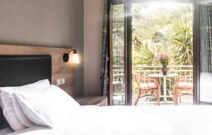 een slaapkamer met een bed en een balkon met een tafel bij The Delfini Hotel in Agia Marina Aegina