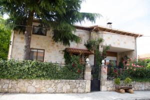 a stone house with a fence and flowers at Casa Rural el Cedro in Abejar