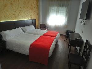 Schlafzimmer mit einem Bett, einem Schreibtisch und einem Fenster in der Unterkunft Hotel Restaurante Sostenible La Laguna in Brozas