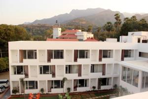a white building with mountains in the background at Saaral Resort By Crossway in Kuttālam