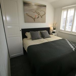 a bedroom with a bed with a black and white comforter at Bungalow Schotvanger in Egmond aan den Hoef