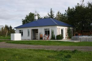 una pequeña casa blanca con techo azul en Jadar Farm en Bær