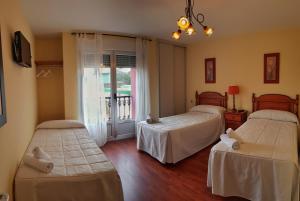 a bedroom with two beds and a balcony at As Eiras Lires Hotel Restaurante in Lires
