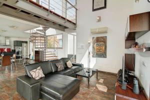 a living room with a black leather couch and a kitchen at Villa Cristal in Tijarafe