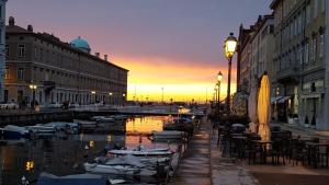 a city street with boats in the water at sunset at Casa vacanza Luisa in Trieste