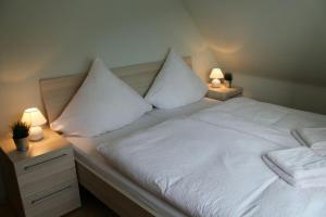 a white bed with two pillows and two lamps at Ferienhaus im Nürburgring in Herschbroich