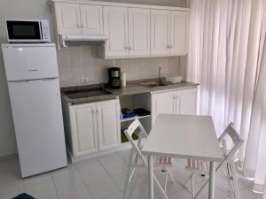 a kitchen with white cabinets and a table and a microwave at Minipiso in Los Llanos de Aridane