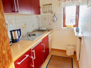 a small kitchen with red cabinets and a sink at Haus-Scheel-2 in Burg auf Fehmarn