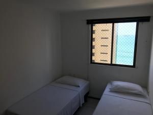two beds in a small room with a window at Atlantic Ocean Residence Sea in Fortaleza
