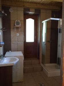 een badkamer met een douche, een wastafel en een deur bij Rebeka Vendégház in Erdőhorváti