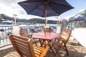 een houten tafel en stoelen met een parasol op een balkon bij Deganwy Hotel in Looe