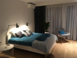 1 dormitorio con cama con sábanas azules y silla en Apartment in the Gantry Hall - W19, en Cracovia