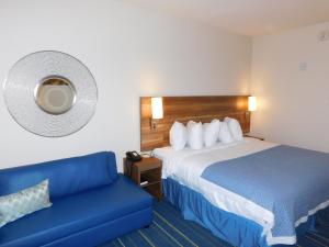 um quarto de hotel com uma cama e um sofá azul em Days Inn & Suites by Wyndham Kearney NE em Kearney