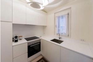 eine Küche mit weißen Schränken, einem Waschbecken und einem Fenster in der Unterkunft Appartamento Il Principe in Porto Cervo