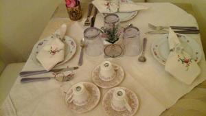 a table with plates and utensils on a white table cloth at Lavanda e Rosmarino in Sandigliano