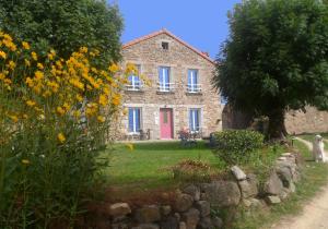 a stone house with a pink door and flowers at Les Cremades in Langogne