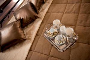 a tray with cups and saucers on a bed at Luxury Relais Cuore Sabino in Stimigliano
