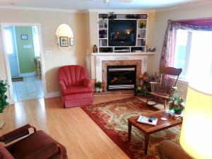 a living room with a fireplace and a red chair at 2 bedroom Wiffen Cottage in Port Albert