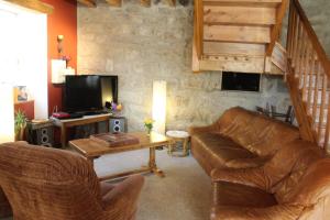 a living room with a leather couch and a television at Les Cremades in Langogne