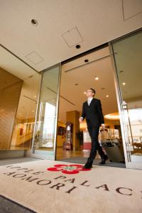 a man in a suit walking in front of a building at Apple Palace Aomori in Aomori