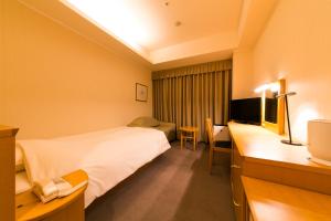 a hotel room with a bed and a desk with a television at Apple Palace Aomori in Aomori