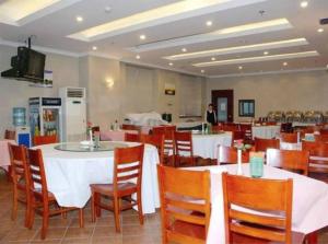 a restaurant with white tables and chairs and a person at Greentree Inn Shanghai Dabaishu Business Hotel in Shanghai