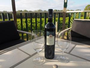 a bottle of wine sitting on a table with two glasses at Bed & Breakfast at Tiffany's in McLaren Vale