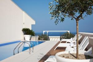 a pool with white chairs and a tree next to it at JR Hotels Bari Grande Albergo delle Nazioni in Bari