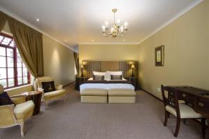 a large bedroom with a bed and a chandelier at Milkwood Lodge in Hermanus