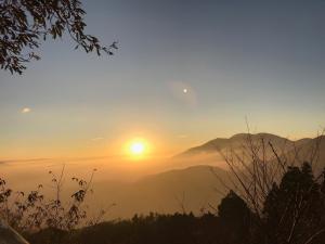 a sunset in the mountains with the sun in the sky at Top Cloud Villa in Renai