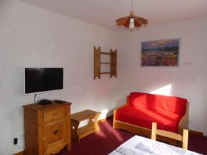 a living room with a red couch and a flat screen tv at Les Lys Orangés in Le Bourg-dʼOisans