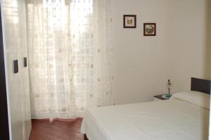 1 dormitorio con 1 cama y una ventana con cortinas blancas en Casa Maria, en Puntalazzo