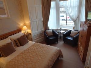 a bedroom with a bed and two chairs and a window at Grange View Bed and Breakfast in Ayr