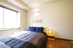 a bedroom with a bed with blue pillows and a window at AKKO's Guest House in Sapporo