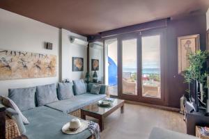 a living room with a blue couch and a large window at Lances Beach Penthouses in Tarifa