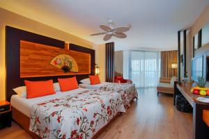 ein Hotelzimmer mit einem großen Bett mit orangefarbenen Kissen in der Unterkunft Limak Lara Deluxe Hotel & Resort Antalya in Lara