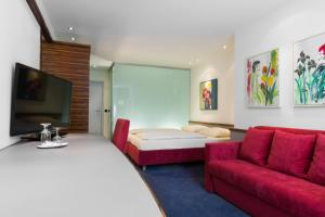 a hotel room with a bed and a couch and a tv at Parkhotel Schillerhöhe in Marbach am Neckar