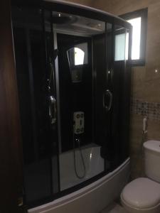 a bathroom with a shower with a toilet and a sink at Koura Nahla Apartment in An Nakhlah +77 photos