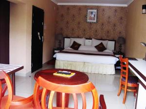 1 dormitorio con 1 cama, mesa y sillas en Lemigo Hotel en Kigali