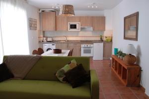カニージャス・デ・アルバイダにあるCasadubislavのリビングルーム(緑のソファ付)、キッチンが備わります。