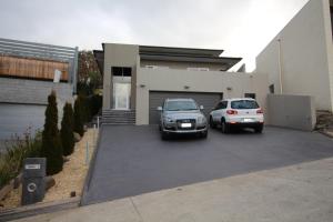 two cars parked in a parking lot in front of a house at Sunny 3 Bedroom Apartment in Sandy Bay in Sandy Bay