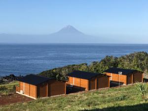 uma fila de casas numa colina perto do oceano em São Jorge Spot - Alojamento em Velas