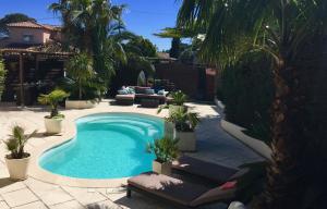 een zwembad in een tuin met palmbomen bij Villa Esterel Plage in Saint-Raphaël
