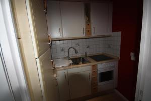 eine kleine Küche mit weißen Schränken und einer Spüle in der Unterkunft Ferienwohnung Wattkieker in Husum + 3 Fotos