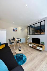 a living room with a couch and a table at Opal'évasion - RDC- Cocon pour 2 pers - 250m de la mer in Berck-sur-Mer